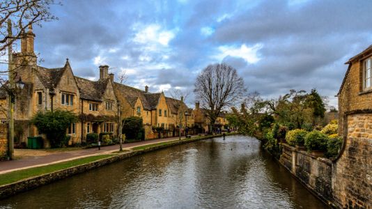 Casa típica inglesa y arroyo en la región de las Cotswolds